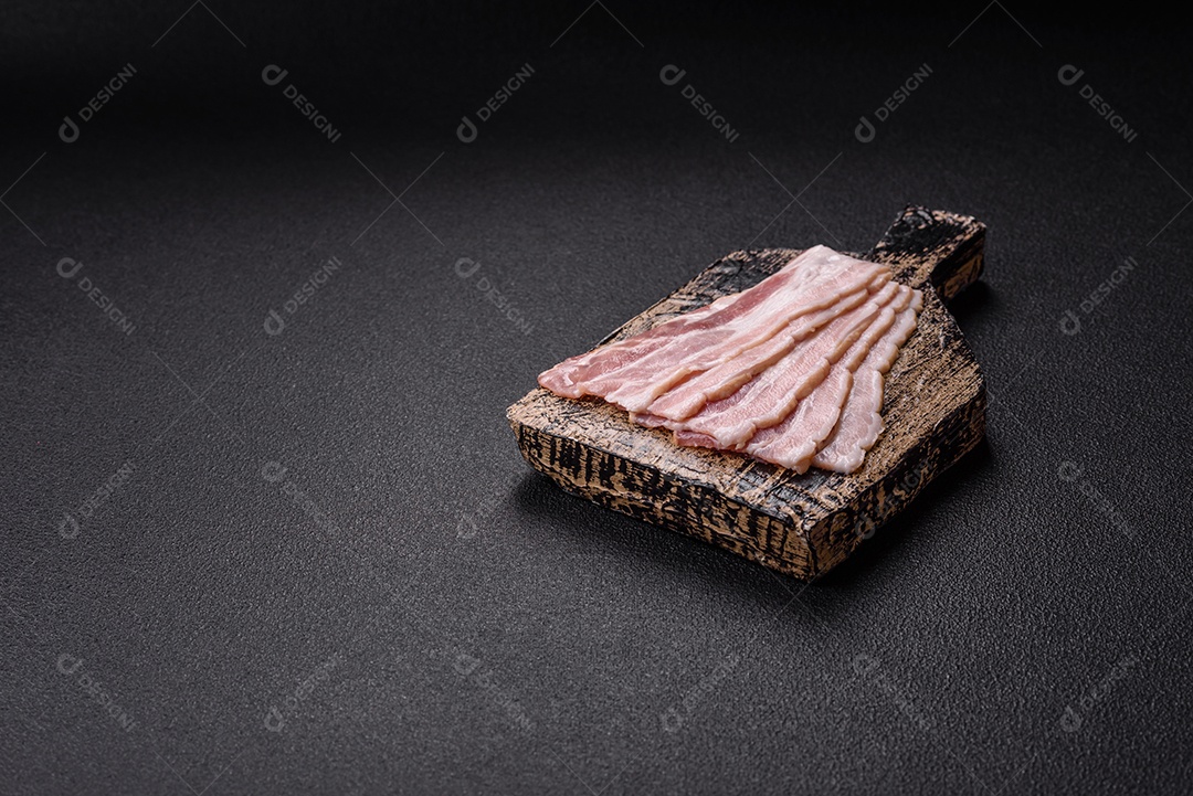Imagem mostra fatias de bacon cru, acompanhadas de tomates cereja e sal rosa.