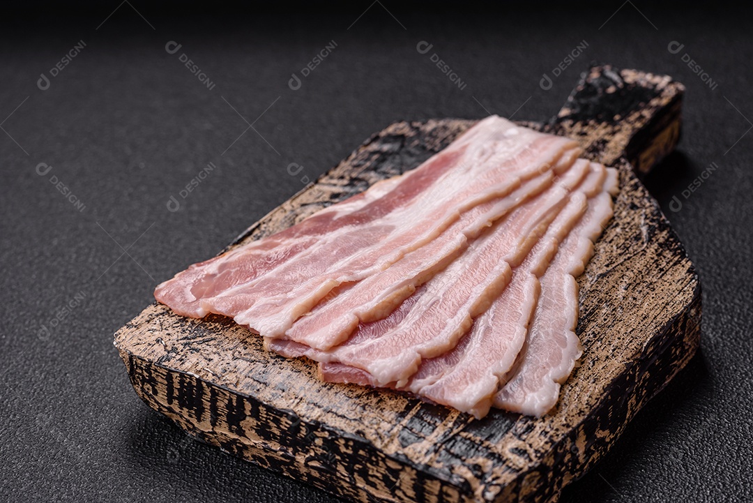 Imagem mostra fatias de bacon cru, acompanhadas de tomates cereja e sal rosa.