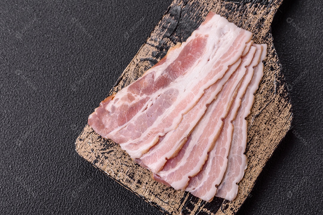 Imagem mostra fatias de bacon cru, acompanhadas de tomates cereja e sal rosa.