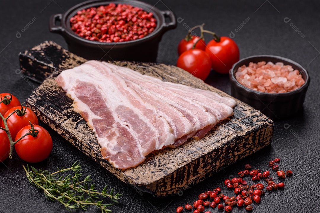 Imagem mostra fatias de bacon cru, acompanhadas de tomates cereja e sal rosa.