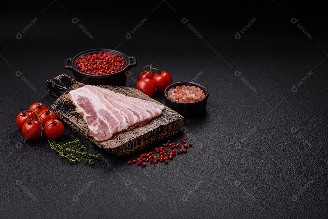 Imagem mostra fatias de bacon cru, acompanhadas de tomates cereja e sal rosa.