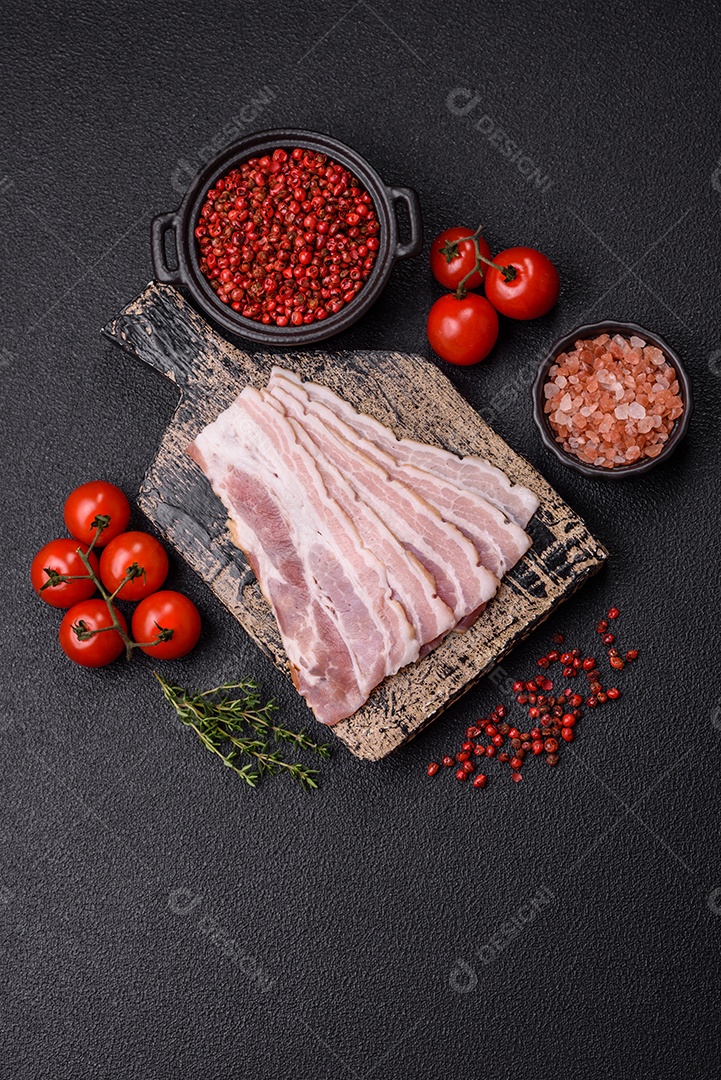 Imagem mostra fatias de bacon cru, acompanhadas de tomates cereja e sal rosa.