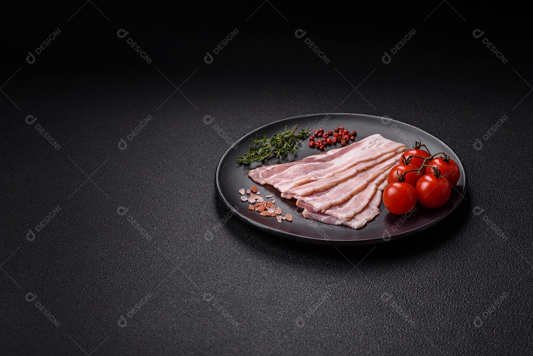 Imagem mostra fatias de bacon cru, acompanhadas de tomates cereja e sal rosa.