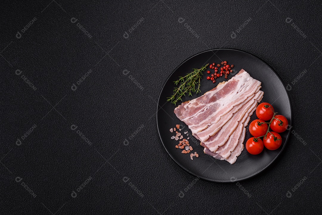 Imagem mostra fatias de bacon cru, acompanhadas de tomates cereja e sal rosa.