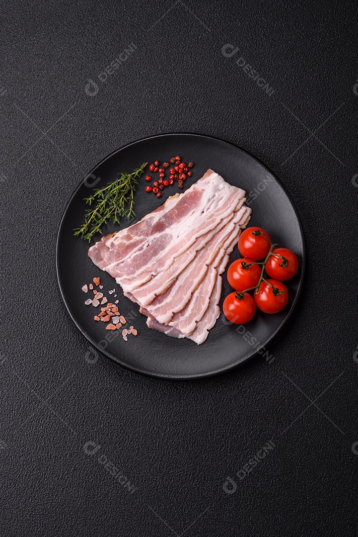 Imagem mostra fatias de bacon cru, acompanhadas de tomates cereja e sal rosa.