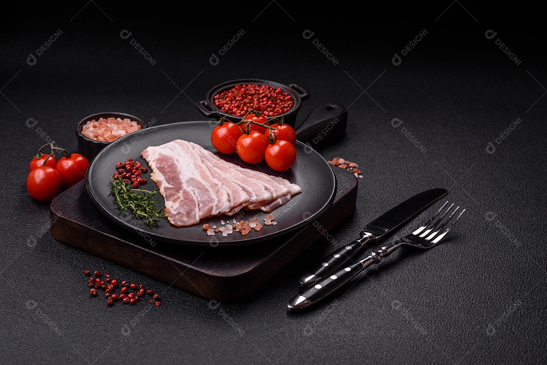 Imagem mostra fatias de bacon cru, acompanhadas de tomates cereja e sal rosa.
