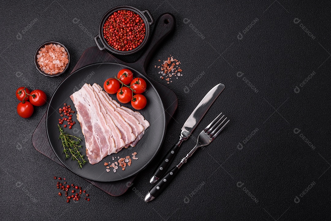 Imagem mostra fatias de bacon cru, acompanhadas de tomates cereja e sal rosa.