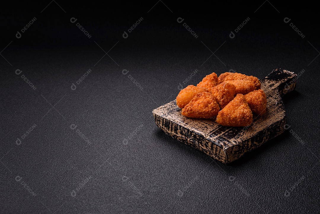 Imagem mostra nuggets de frango com molho e alguns grãos de pimenta rosa