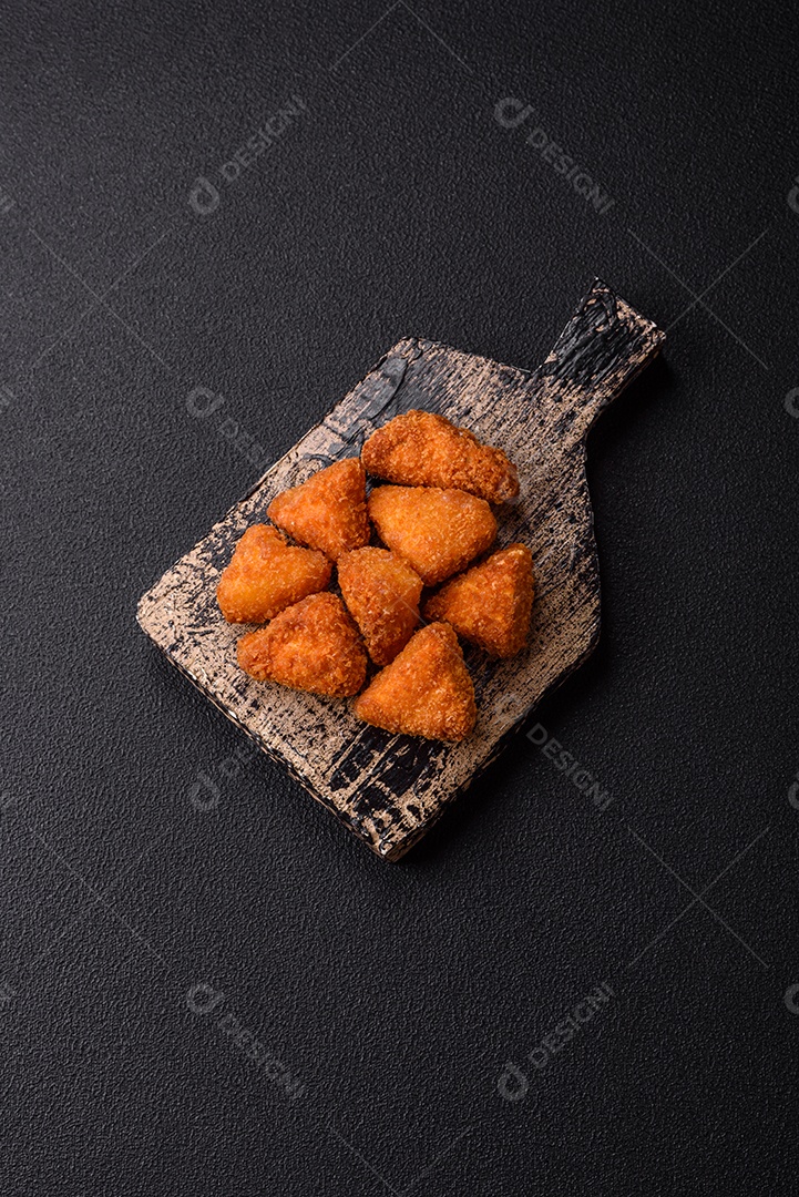 Imagem mostra nuggets de frango com molho e alguns grãos de pimenta rosa