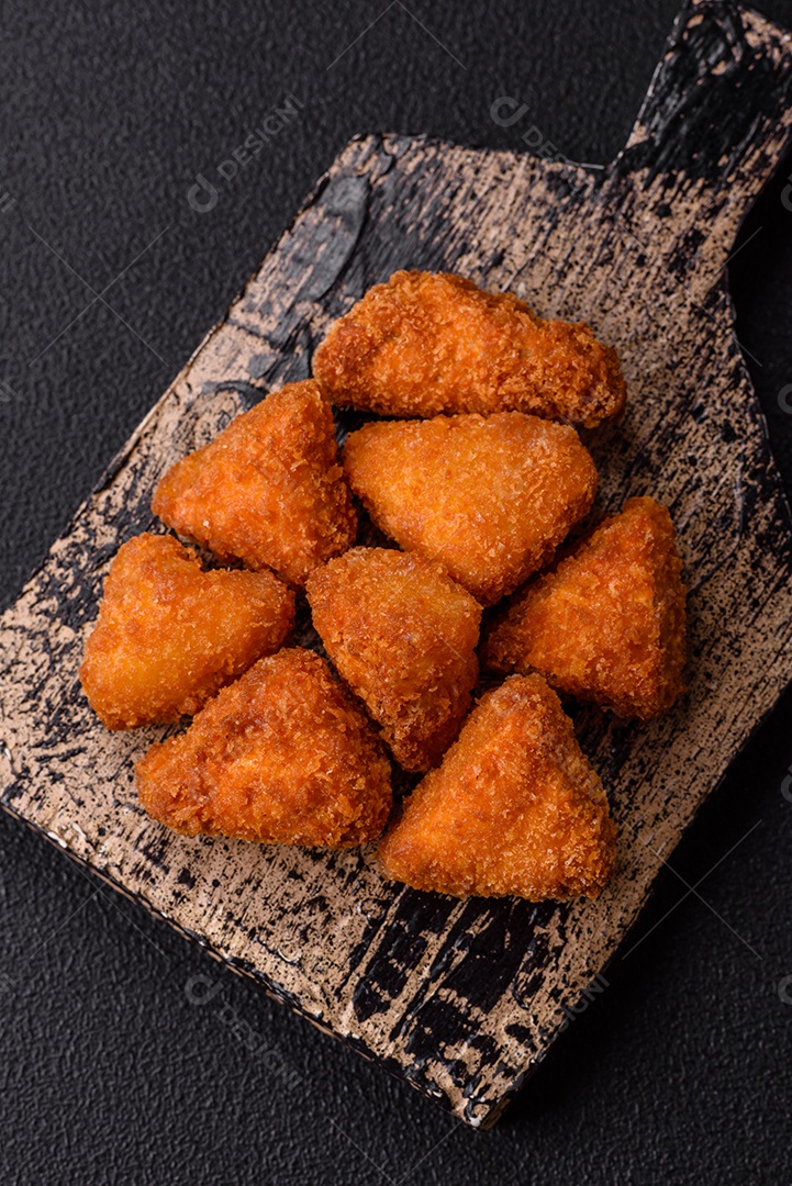 Imagem mostra nuggets de frango com molho e alguns grãos de pimenta rosa