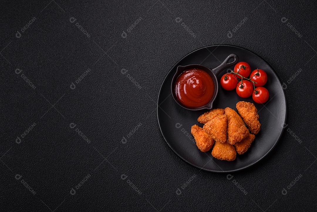 Imagem mostra nuggets de frango com molho e alguns grãos de pimenta rosa