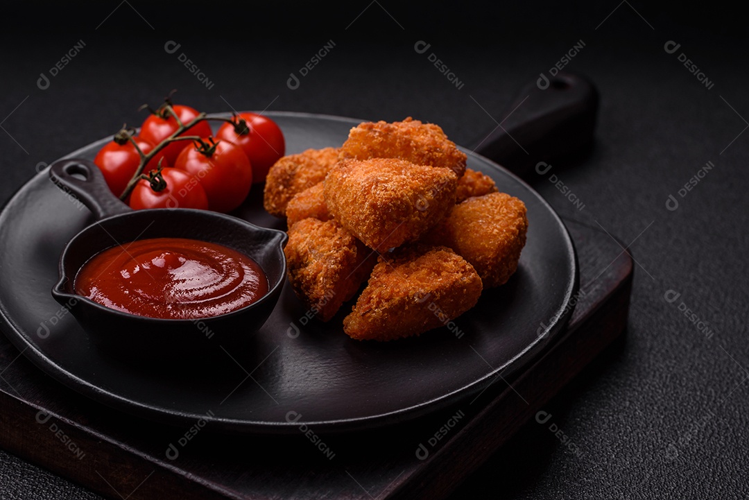 Imagem mostra nuggets de frango com molho e alguns grãos de pimenta rosa