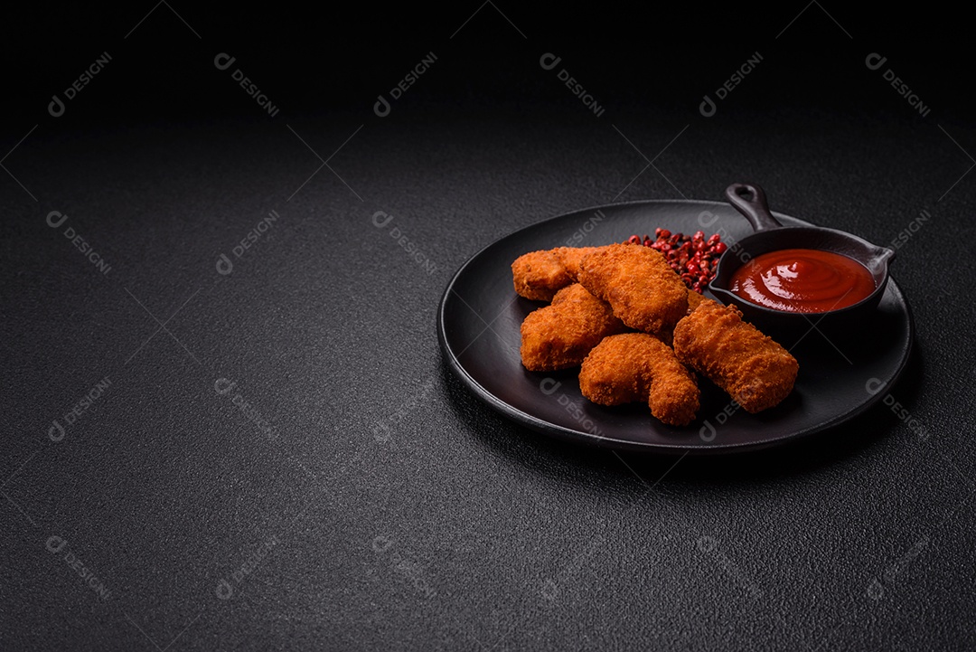 Imagem mostra nuggets de frango com molho e alguns grãos de pimenta rosa