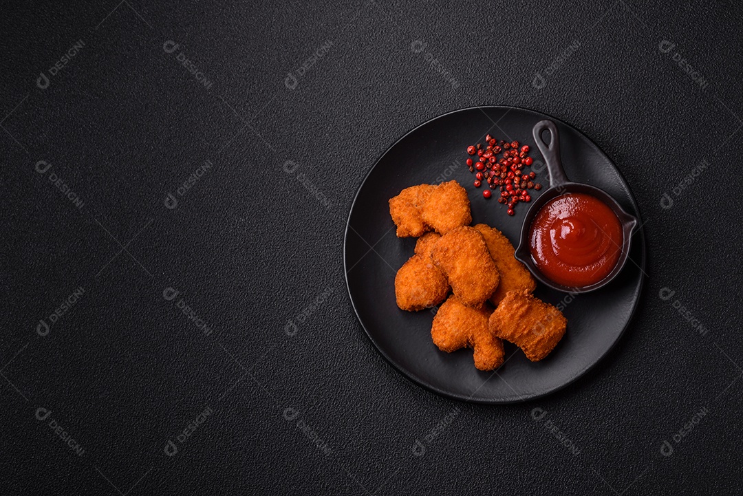 Imagem mostra nuggets de frango com molho e alguns grãos de pimenta rosa