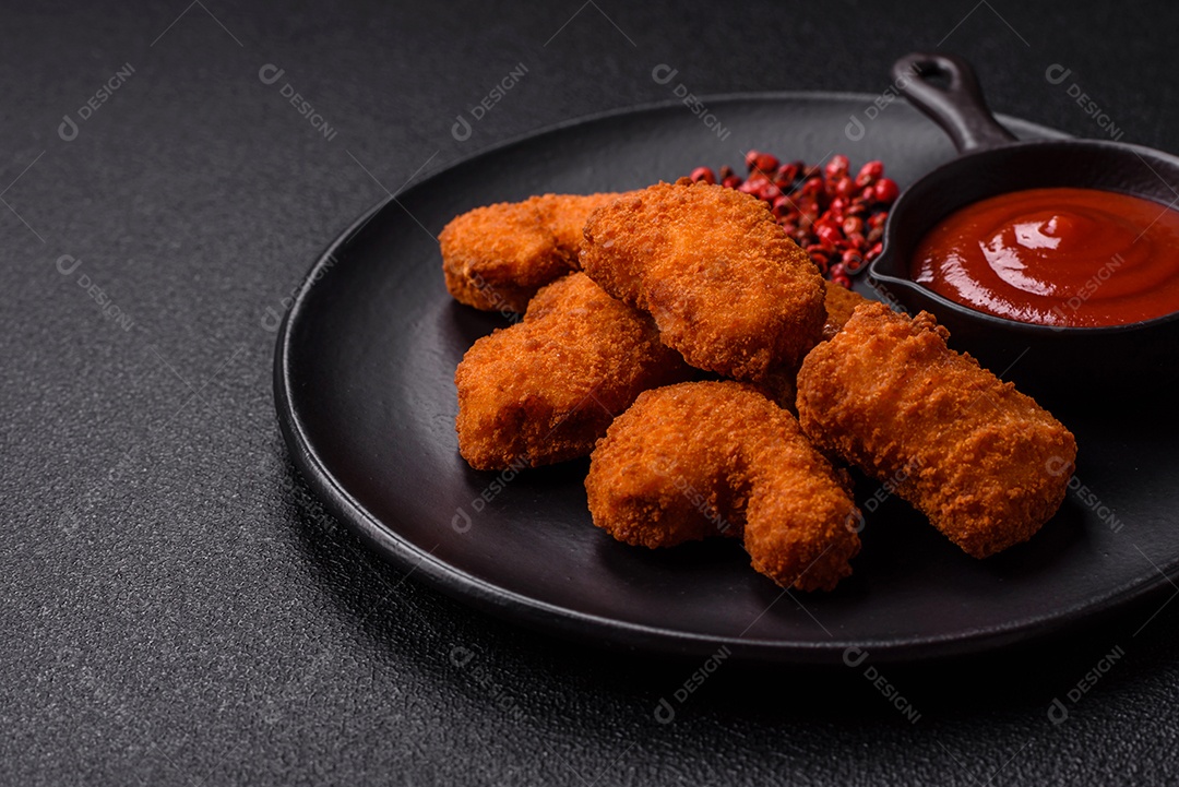 Imagem mostra nuggets de frango com molho e alguns grãos de pimenta rosa