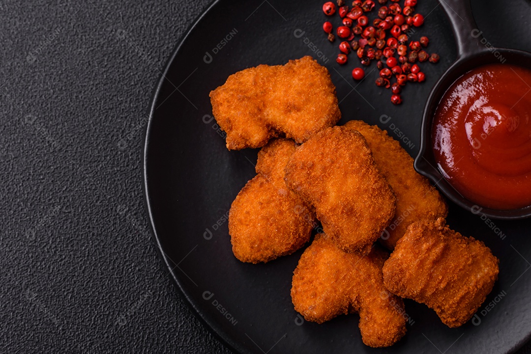 Imagem mostra nuggets de frango com molho e alguns grãos de pimenta rosa