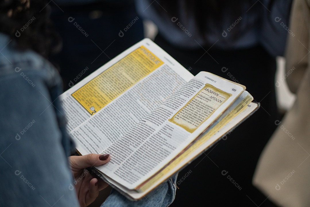Mão de uma mulher segurando uma bíblia sob uma igreja