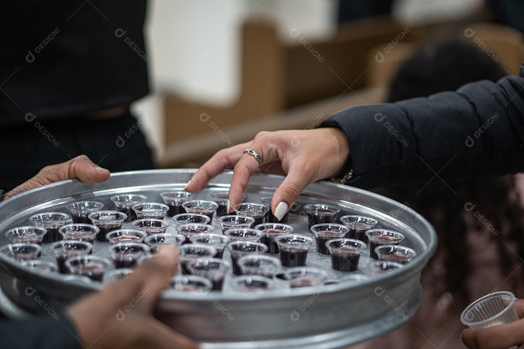 Mão de uma mulher pegando santa ceia em uma bandeija sob uma igreja