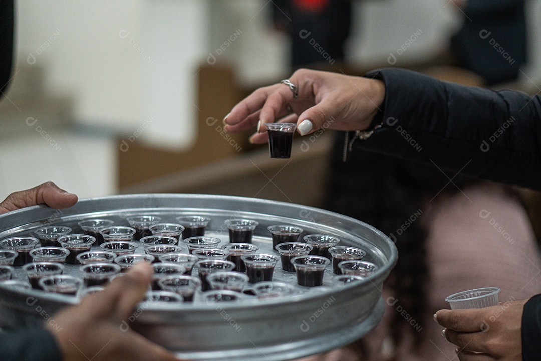 Mão de uma mulher pegando santa ceia em uma bandeija sob uma igreja
