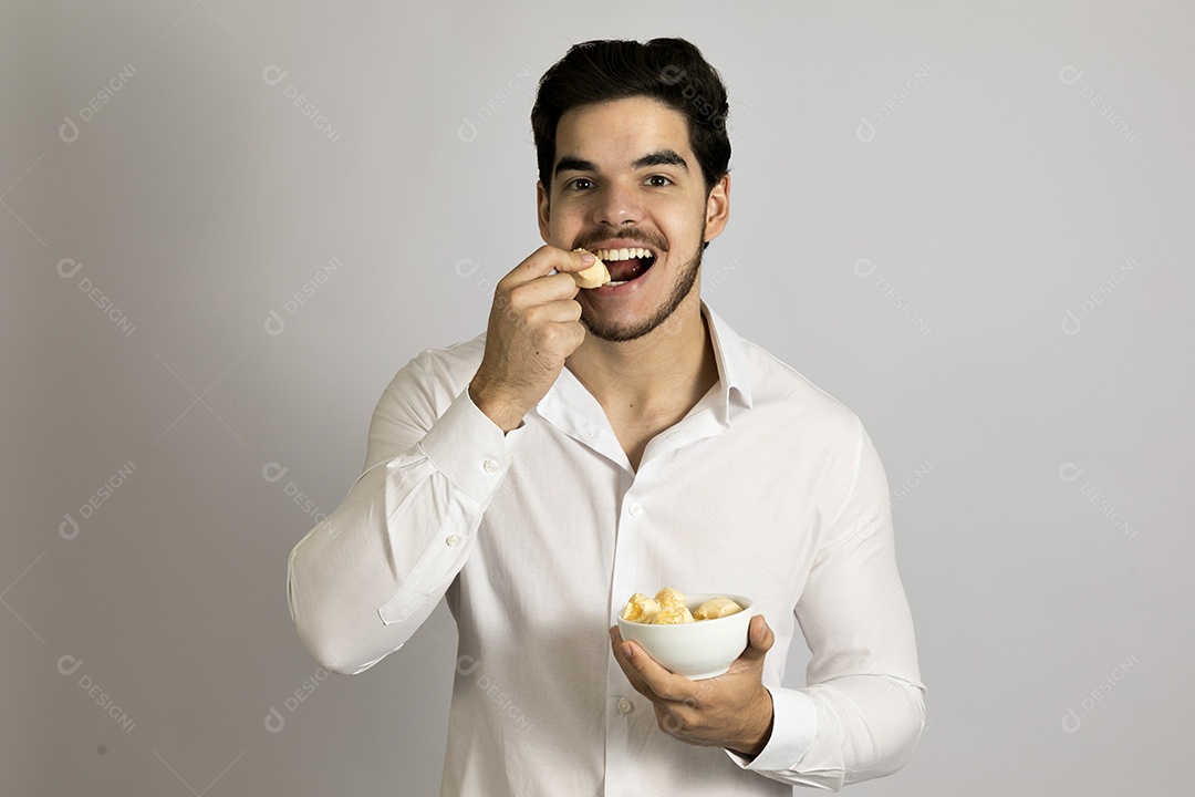 Homem jovem bonito comendo bolo sobre fundo isolado branco
