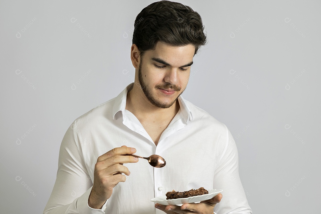 Homem jovem bonito comendo bolo sobre fundo isolado branco