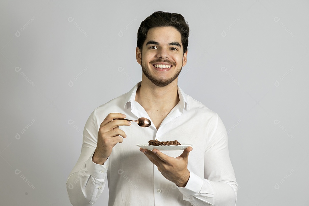 Homem jovem bonito comendo bolo sobre fundo isolado branco