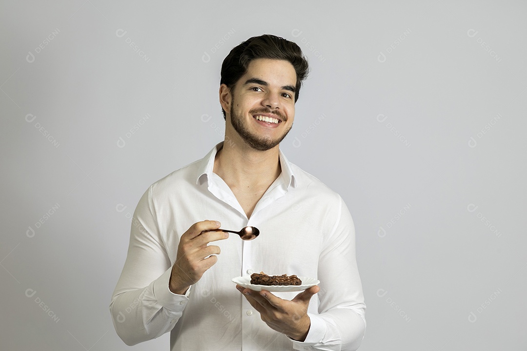 Homem jovem bonito comendo bolo sobre fundo isolado branco