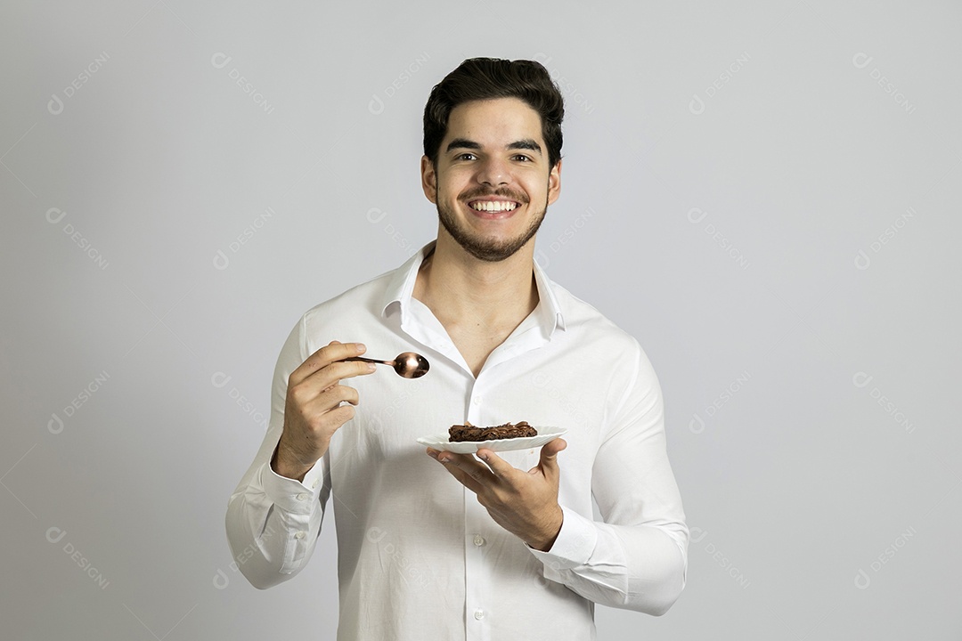 Homem jovem bonito comendo bolo sobre fundo isolado branco