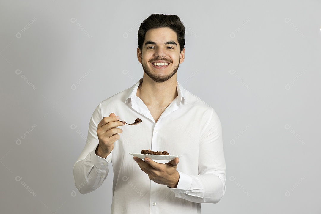 Homem jovem bonito comendo bolo sobre fundo isolado branco