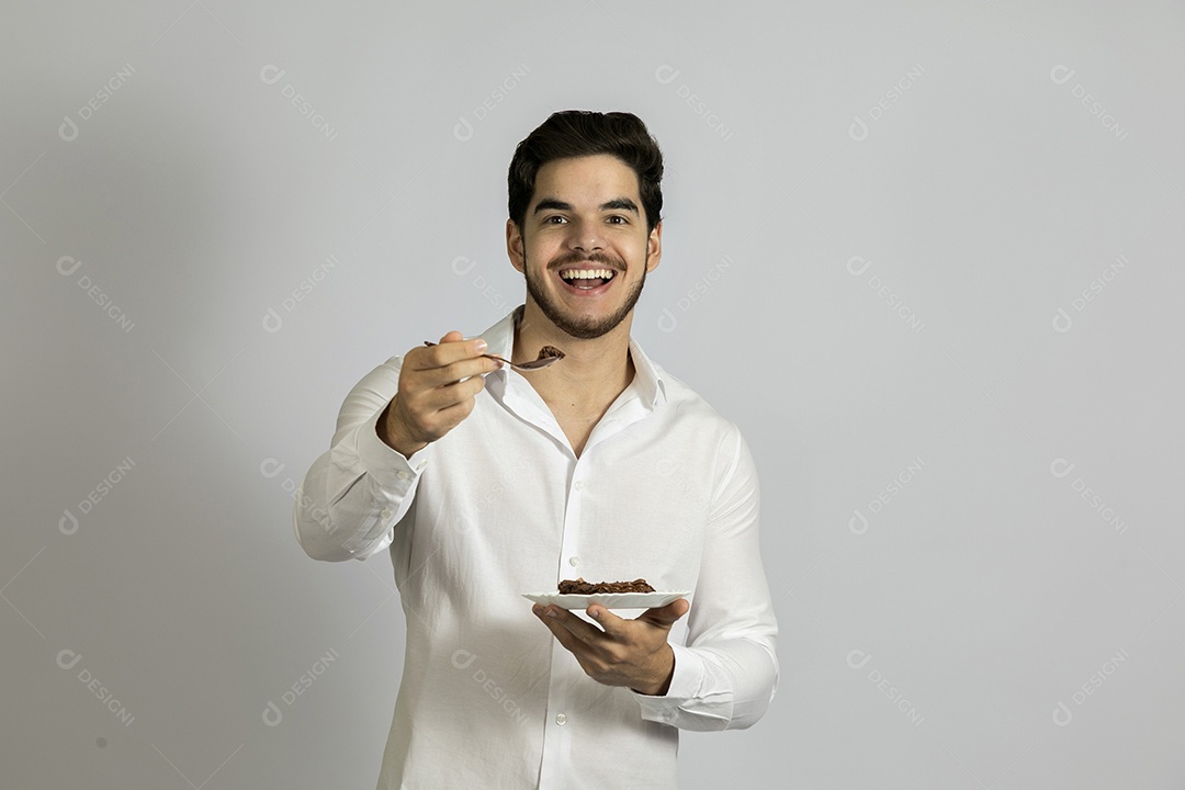 Homem jovem bonito comendo bolo sobre fundo isolado branco