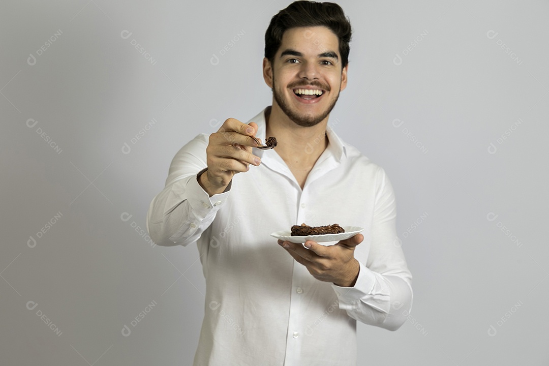 Homem jovem bonito comendo bolo sobre fundo isolado branco