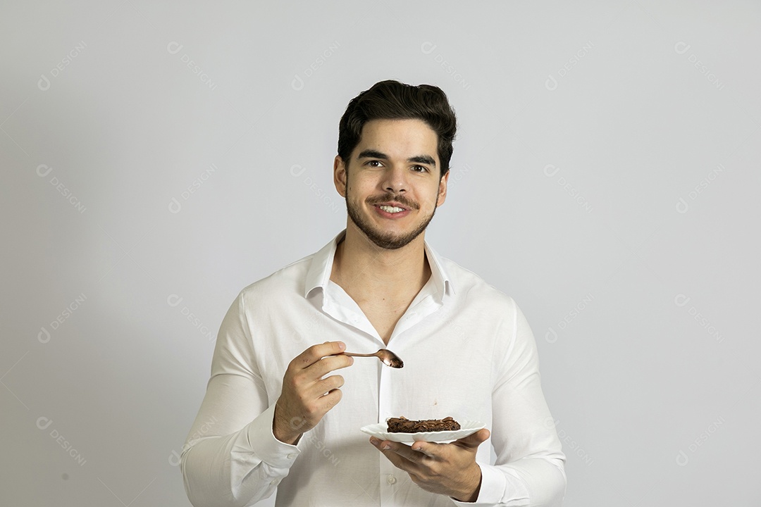 Homem jovem bonito comendo bolo sobre fundo isolado branco