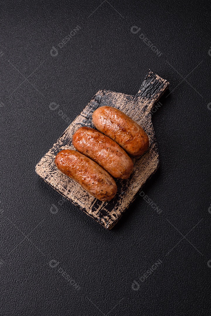 Imagem mostra um prato com salsichas grelhadas ou assadas, acompanhadas de legumes e temperos.