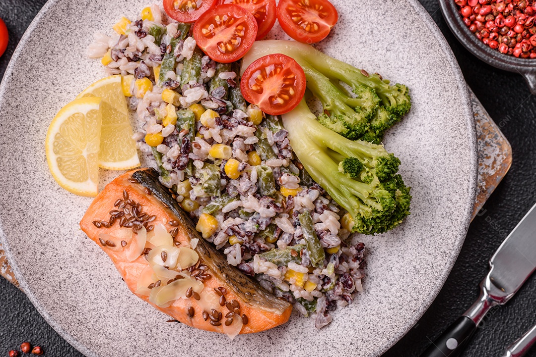 Imagem mostra um prato de salmão grelhado acompanhado de brócolis e arroz com legumes, decorado com uma fatia de limão e tomate