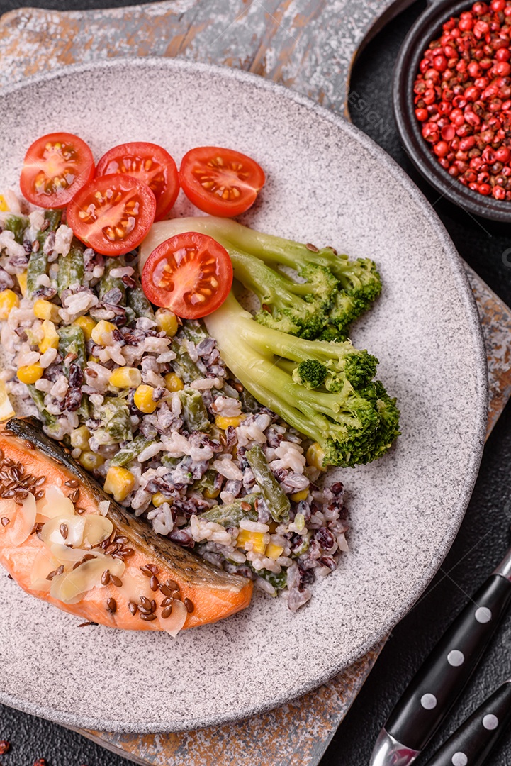 Imagem mostra um prato de salmão grelhado acompanhado de brócolis e arroz com legumes, decorado com uma fatia de limão e tomate