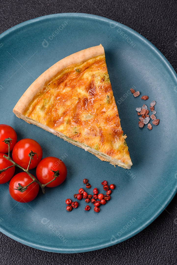 Imagem mostra uma fatia de quiche, acompanhada de tomates-cereja e grãos de pimenta rosa