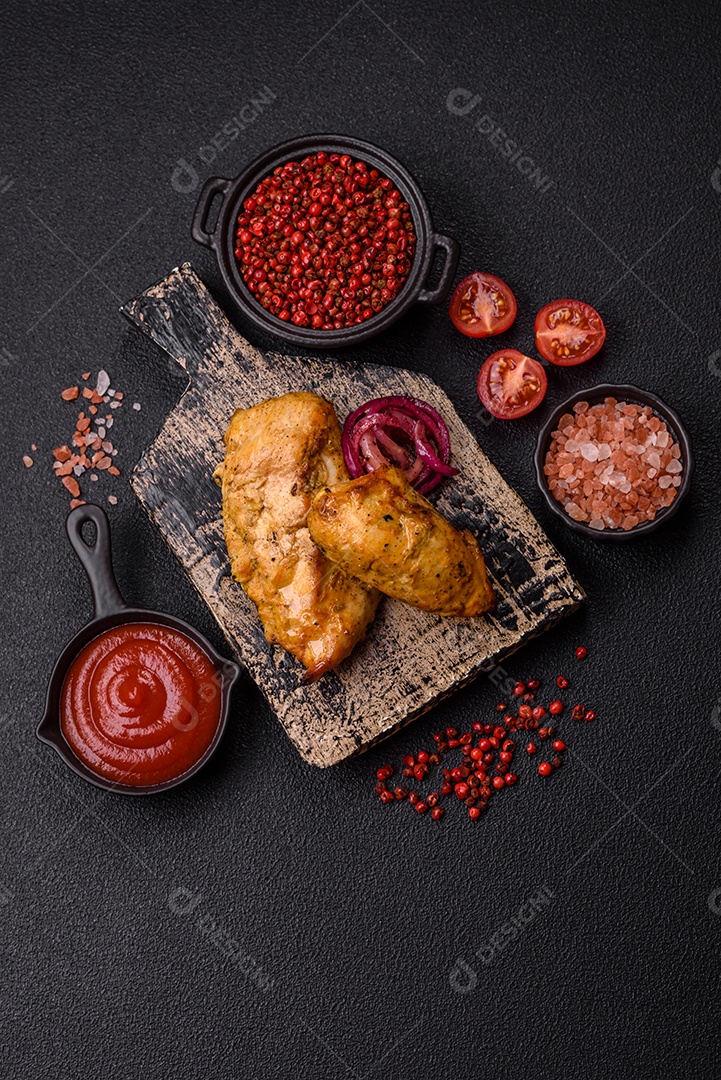 Filés de frango grelhados ou assados, acompanhados de tomates cereja, cebola roxa em rodelas e alguns temperos ou especiarias em grãos e em pó. Há também um molho vermelho em um recipiente separado, que pode ser ketchup ou outro molho à base de tomate