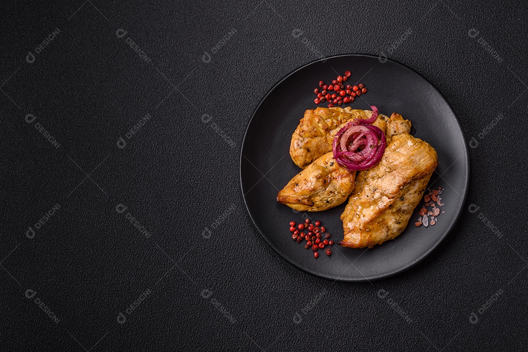 Filés de frango grelhados ou assados, acompanhados de tomates cereja, cebola roxa em rodelas e alguns temperos ou especiarias em grãos e em pó. Há também um molho vermelho em um recipiente separado, que pode ser ketchup ou outro molho à base de tomate