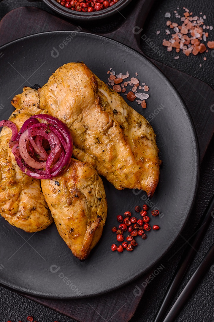 Filés de frango grelhados ou assados, acompanhados de tomates cereja, cebola roxa em rodelas e alguns temperos ou especiarias em grãos e em pó. Há também um molho vermelho em um recipiente separado, que pode ser ketchup ou outro molho à base de tomate