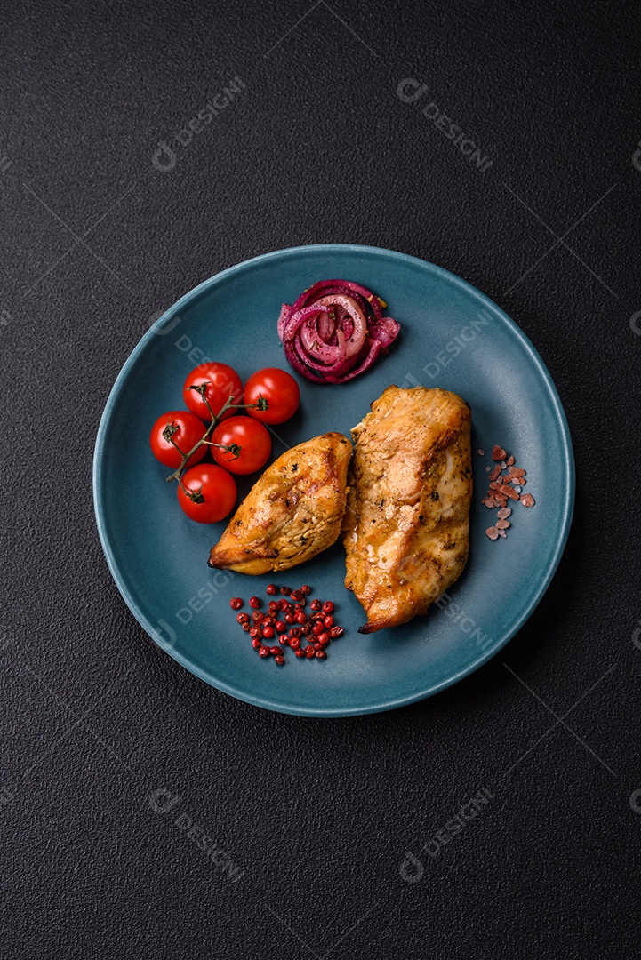Filés de frango grelhados ou assados, acompanhados de tomates cereja, cebola roxa em rodelas e alguns temperos ou especiarias em grãos e em pó. Há também um molho vermelho em um recipiente separado, que pode ser ketchup ou outro molho à base de tomate