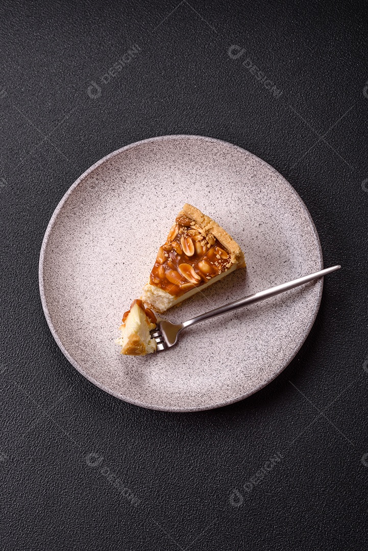 A imagem mostra uma fatia de cheesecake, possivelmente com uma cobertura de caramelo e nozes.
