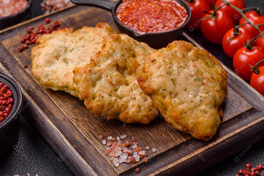 A imagem mostra dois bolinhos de carne fritos, acompanhados de um molho vermelho