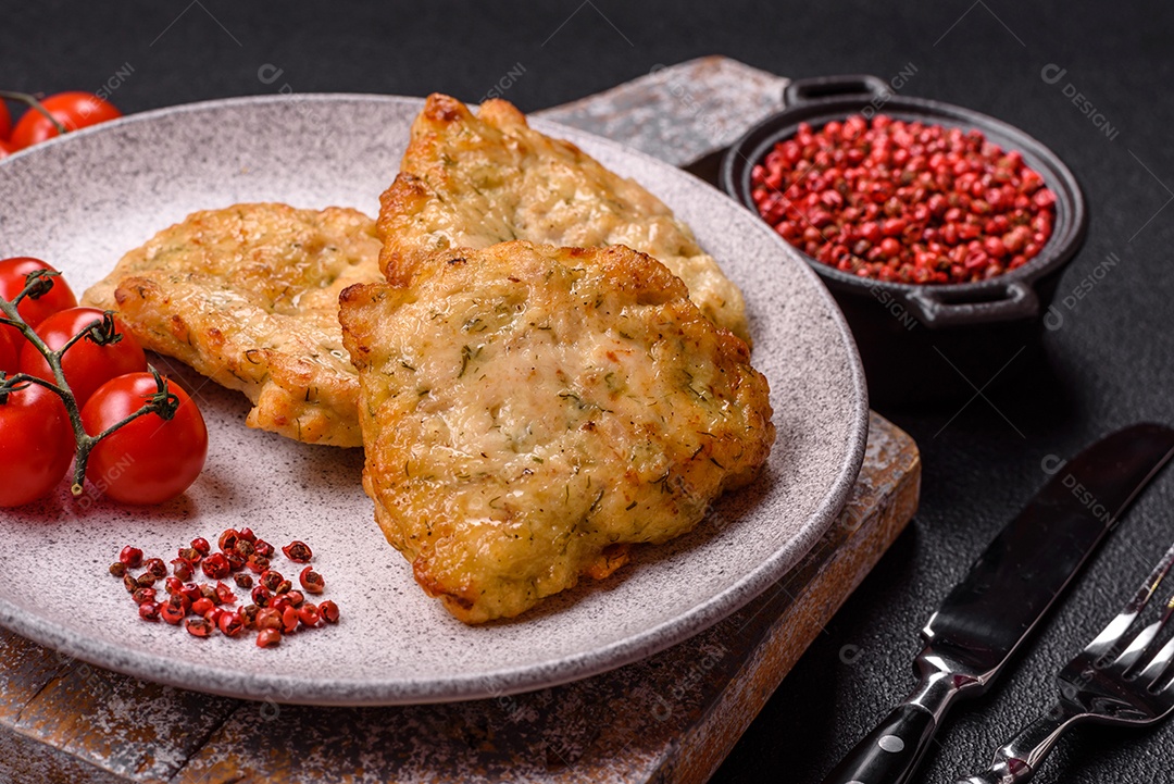 A imagem mostra pedaços de frango frito servidos em uma tábua de madeira com temperos e molho.