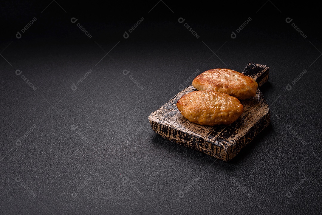 A imagem mostra dois bolinhos de carne fritos, acompanhados de um molho vermelho
