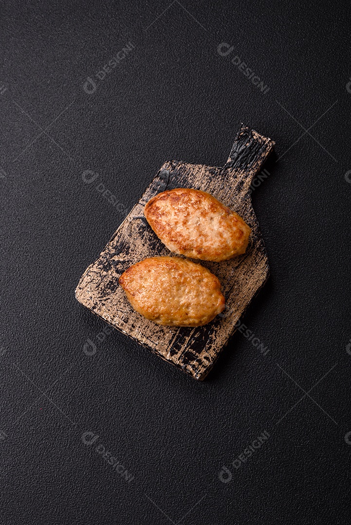 A imagem mostra dois bolinhos de carne fritos, acompanhados de um molho vermelho