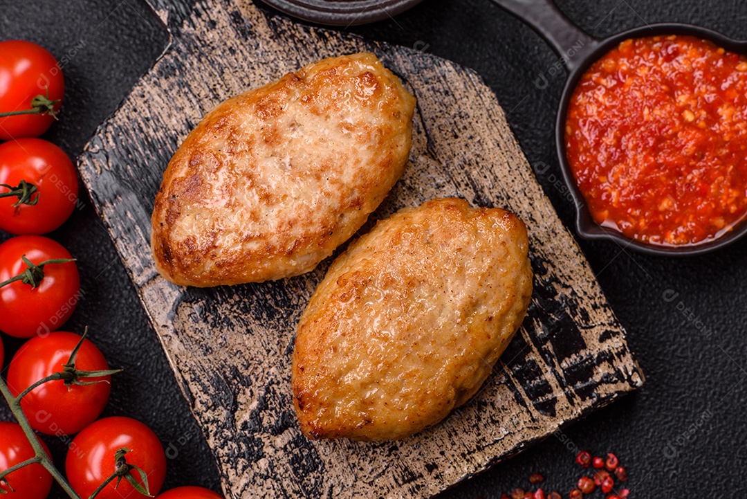 A imagem mostra dois bolinhos de carne fritos, acompanhados de um molho vermelho