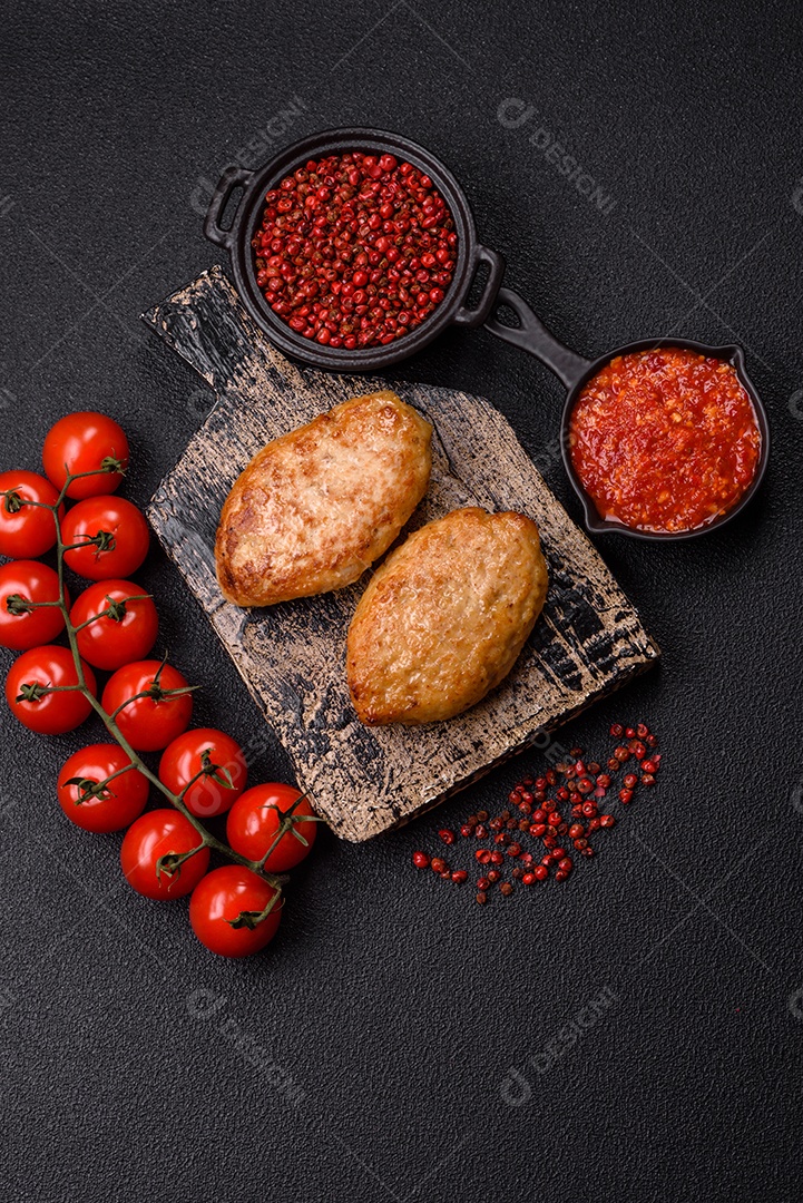 A imagem mostra dois bolinhos de carne fritos, acompanhados de um molho vermelho