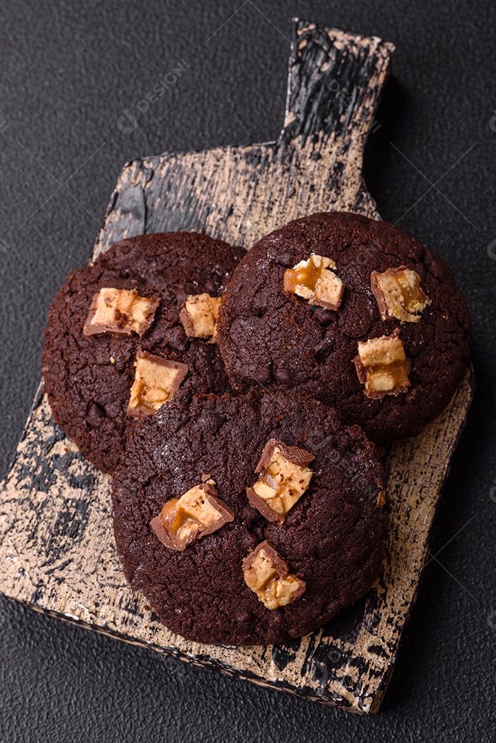 A imagem mostra biscoitos de chocolate, possivelmente cookies, decorados com pedaços de chocolate