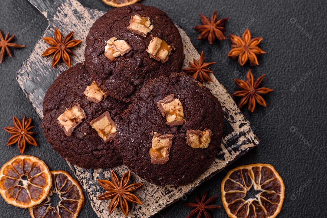 A imagem mostra biscoitos de chocolate, possivelmente cookies, decorados com pedaços de chocolate