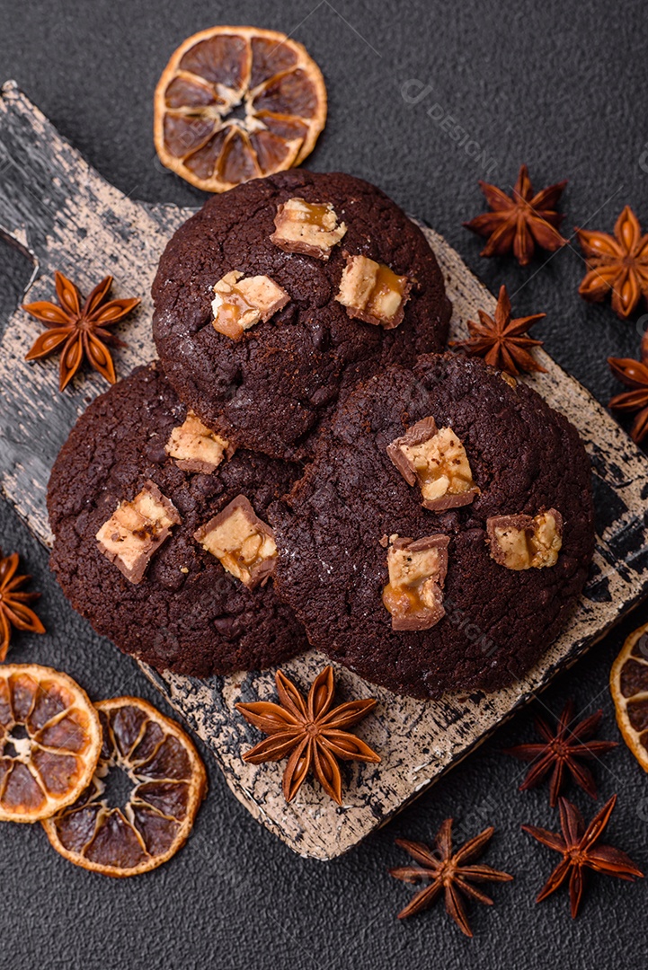 A imagem mostra biscoitos de chocolate, possivelmente cookies, decorados com pedaços de chocolate